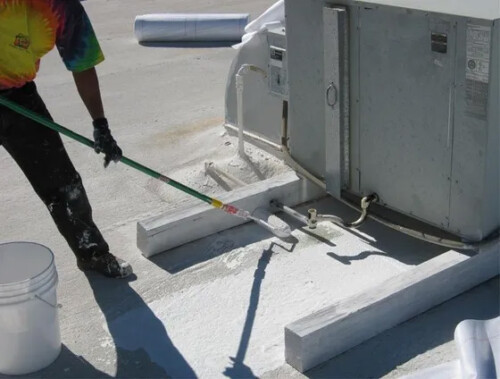 Spreading Sunland Coating's white elastomeric roof coating around an airconditioning unit on a flat roof in Arizona.